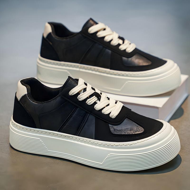 A pair of low-top platform sneakers in black and white, featuring a chunky white sole, white laces, and black leather panels with a subtle textured accent on the sides.