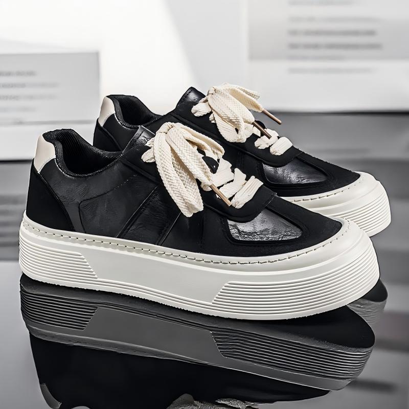 A pair of low-top platform sneakers in black and white, featuring chunky off-white platform soles, thick off-white laces, and textured black panels, displayed on a reflective dark surface.