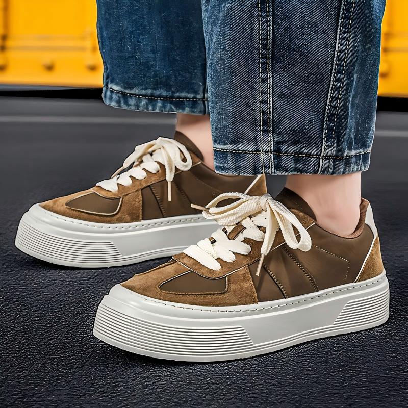 A pair of low-top platform sneakers in brown suede and smooth brown fabric, with off-white laces and thick ridged white soles, shown on a person wearing blue jeans.
