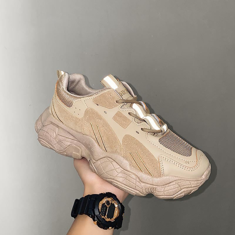 Beige sneaker held by a hand against a gray background