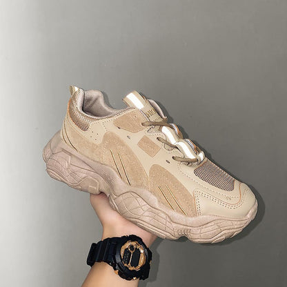 Beige sneaker held by a hand against a gray background