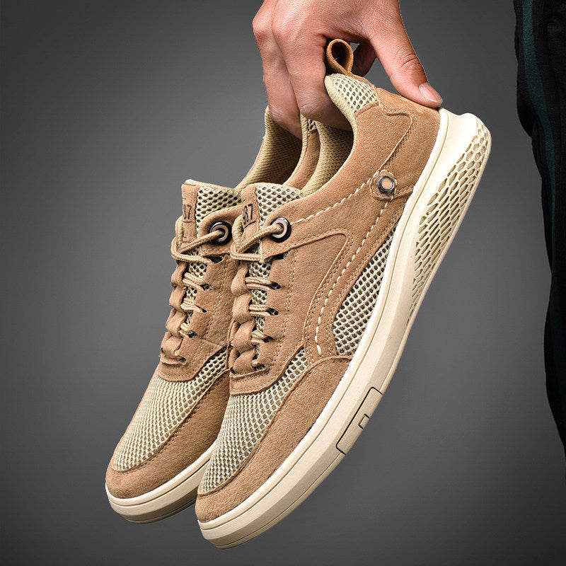 Beige sneakers being held against a dark background