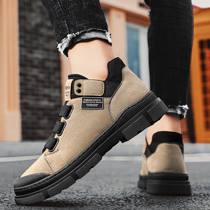 Beige work boots with black soles worn by a person on a blurred background