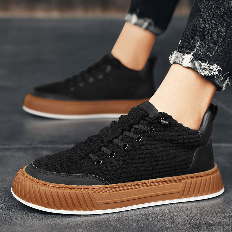 Black and brown sneakers worn by a person on a dark surface