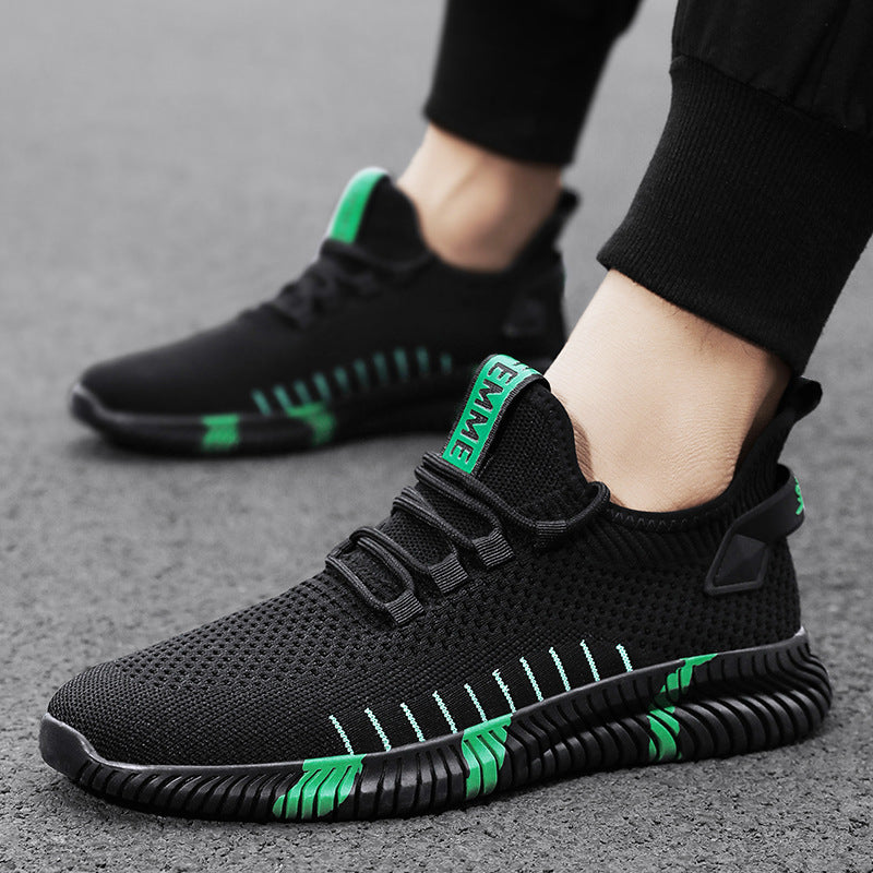 Black and green athletic shoes worn by a person on a gray surface