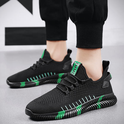 Black and green sneakers worn with black pants on a light gray floor.
