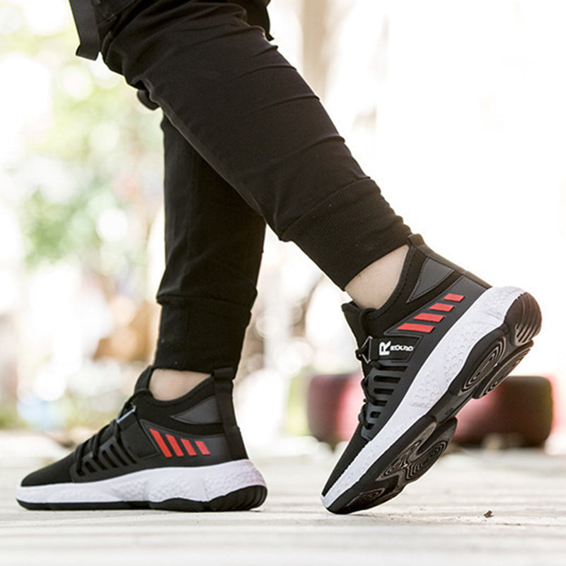 Black and red athletic shoes worn with black pants on a blurred background