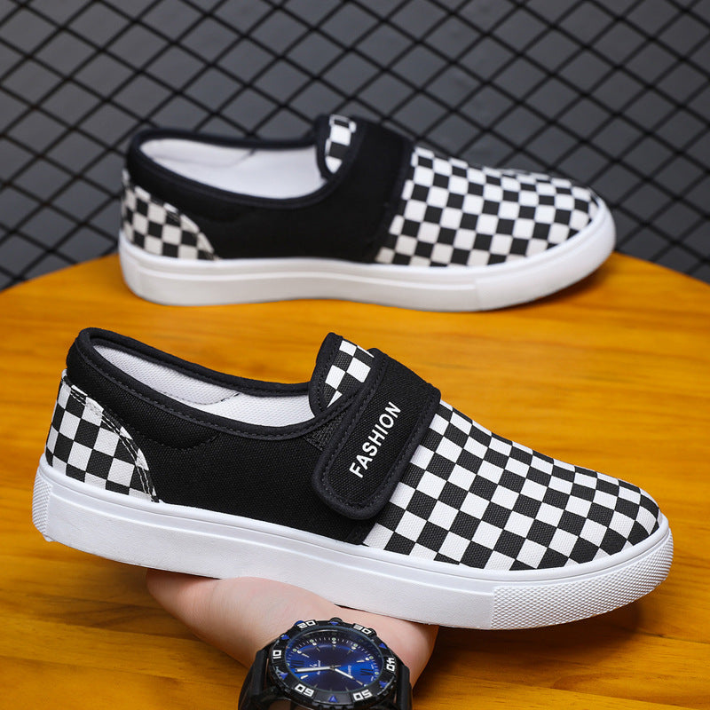 Black and white checkered shoes with velcro straps on a wooden surface.