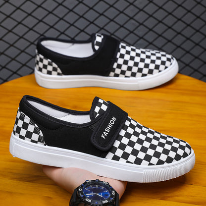 Black and white checkered shoes with velcro straps on a wooden surface.