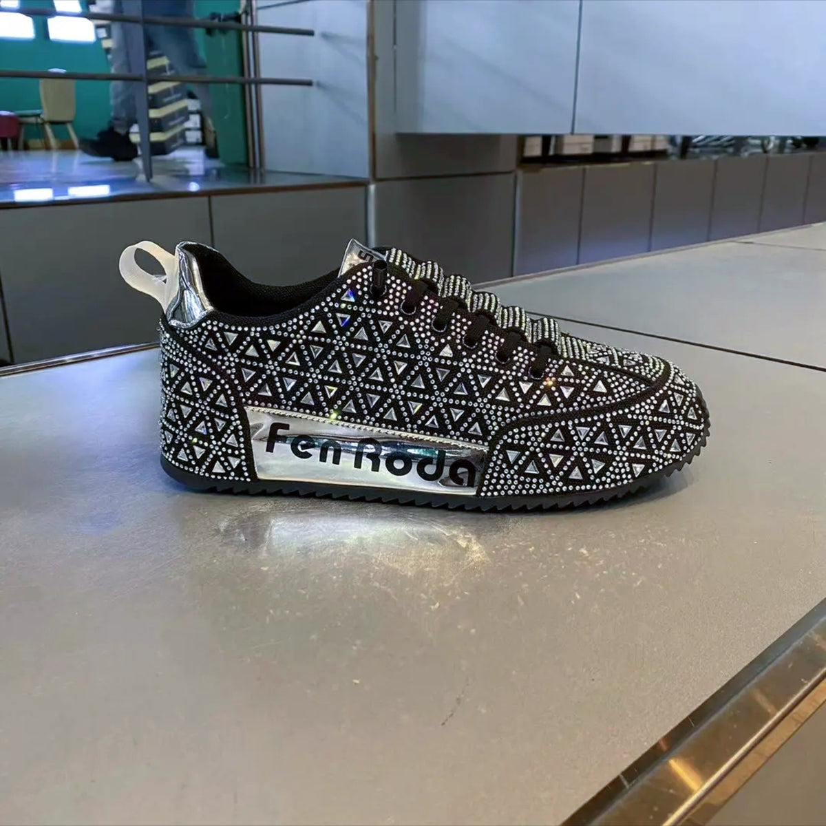 Black and white patterned shoe with 'fenRoda' branding on a reflective surface.