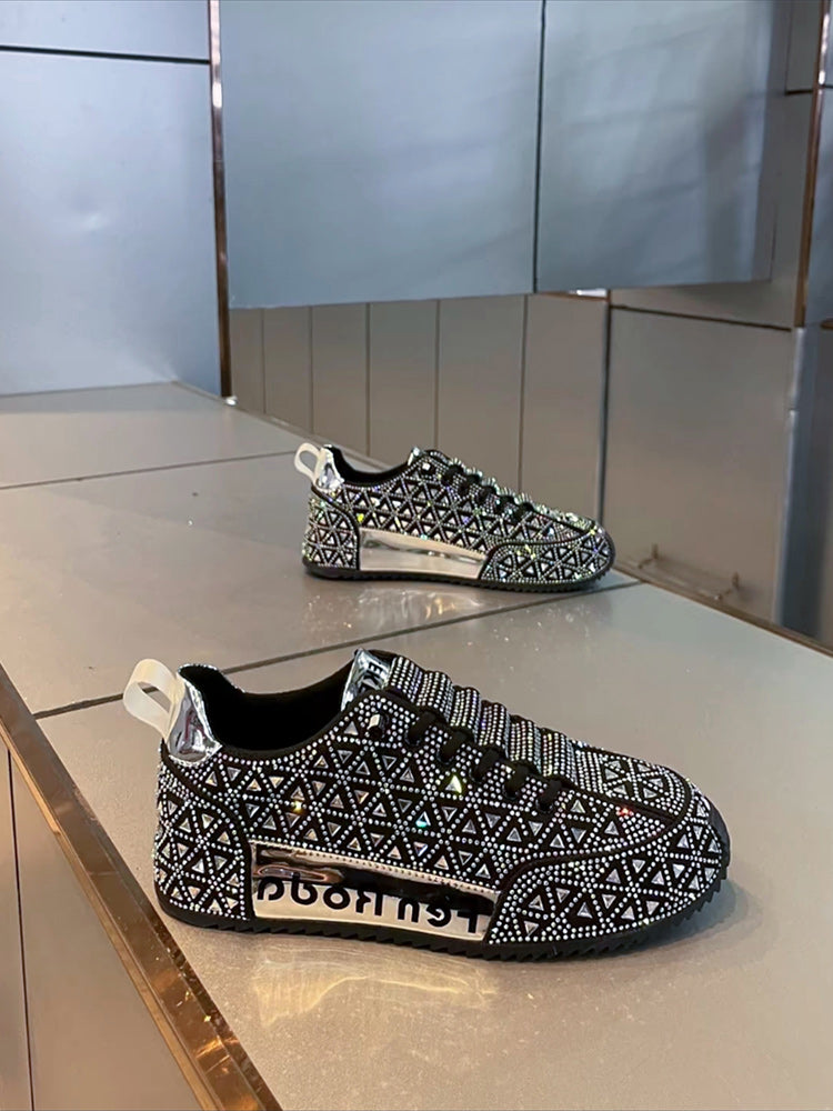 Black and white patterned sneakers with rhinestone embellishments on a reflective surface.