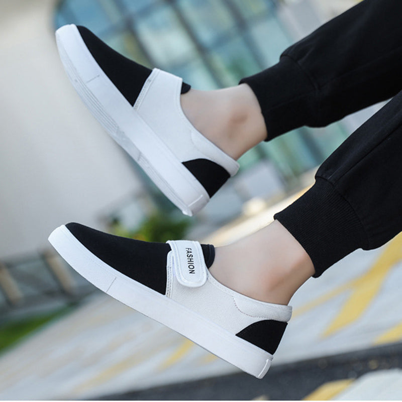 Black and white slip-on shoes with 'FASHION' label worn by a person.