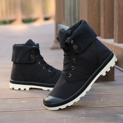 Black high-top boots with white soles on a wooden surface