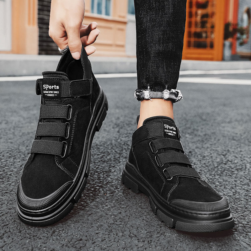 Black high-top sneakers with velcro straps on a street background