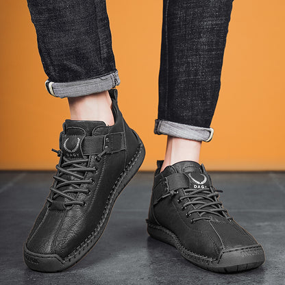 Black leather boots worn with rolled-up jeans against an orange background