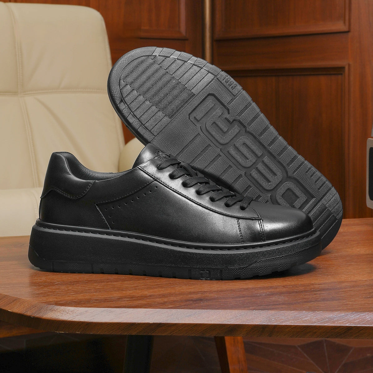 Black leather shoes on a wooden table with a beige chair and wooden cabinet in the background.