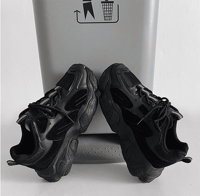 Black sneakers in front of a gray trash can with a black foot icon.