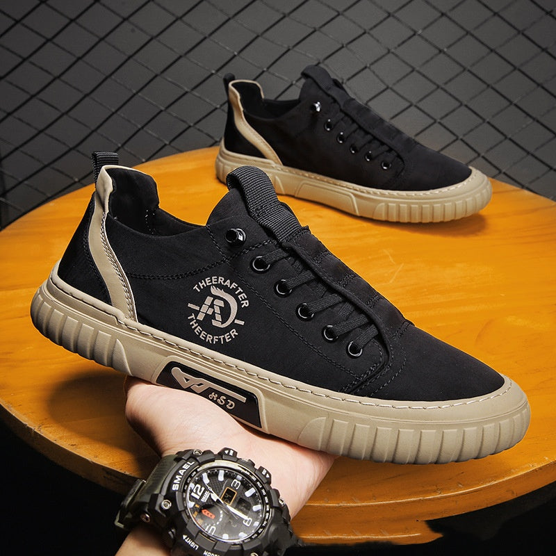 Black sneakers with beige accents on a wooden surface, worn by a person with a watch.