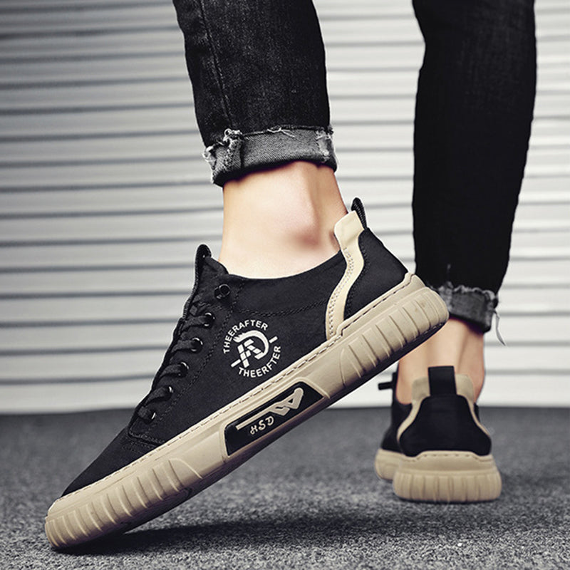 Black sneakers with beige soles worn by a person against a neutral background