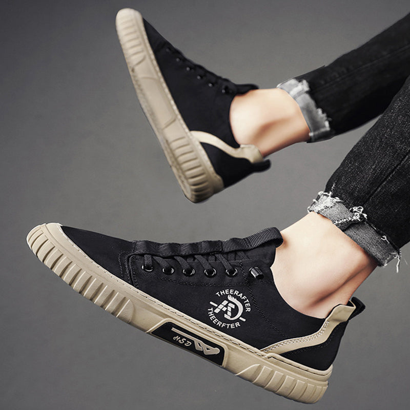 Black sneakers with beige soles worn by a person on a gray background