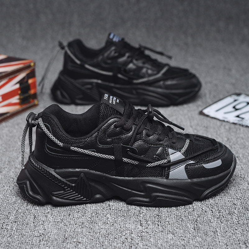 Black sneakers with chain details on a gray surface