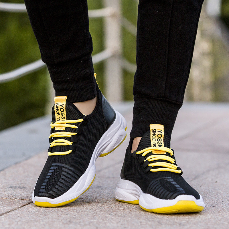 Black sneakers with yellow laces and sole on a blurred outdoor background
