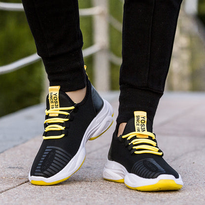 Black sneakers with yellow laces and sole on a blurred outdoor background