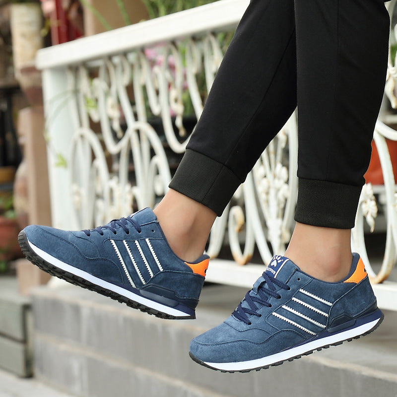 Blue sneakers with orange accents worn by a person on a blurred outdoor background