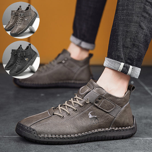 Brown leather shoes worn with dark jeans on a gray floor.