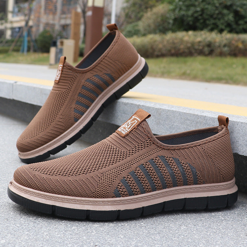 Brown slip-on shoes with black soles on a concrete surface.