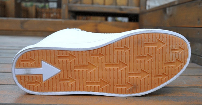 Close-up of a white sneaker with brown sole on a wooden surface