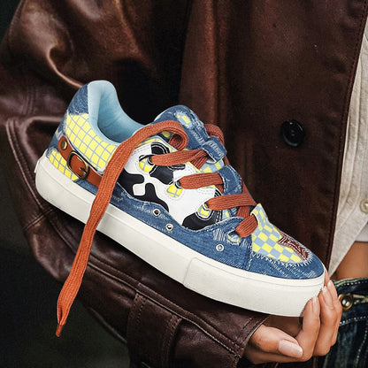 Colorful sneaker with denim pattern held by a person wearing a brown coat.