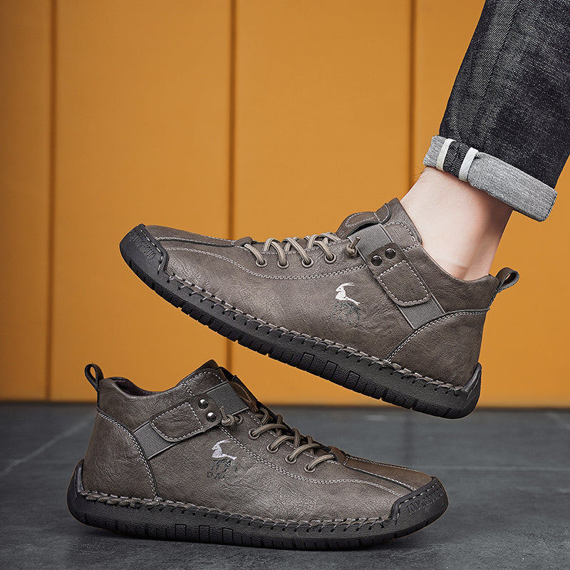 Gray casual shoes with a brand logo worn by a person against a yellow wall.
