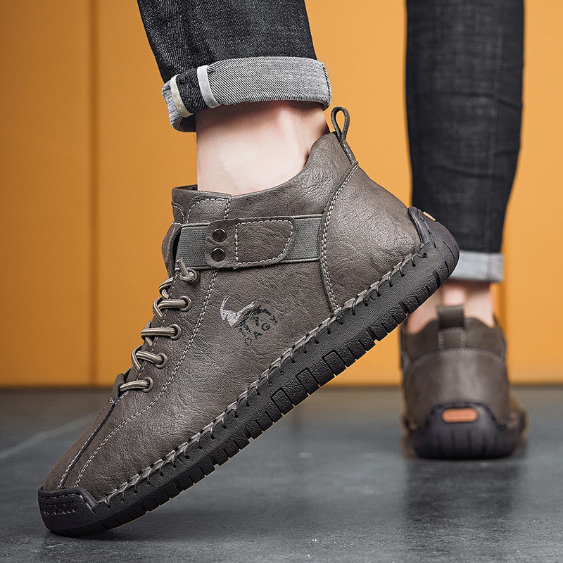 Gray leather boots worn with rolled-up jeans against a yellow background