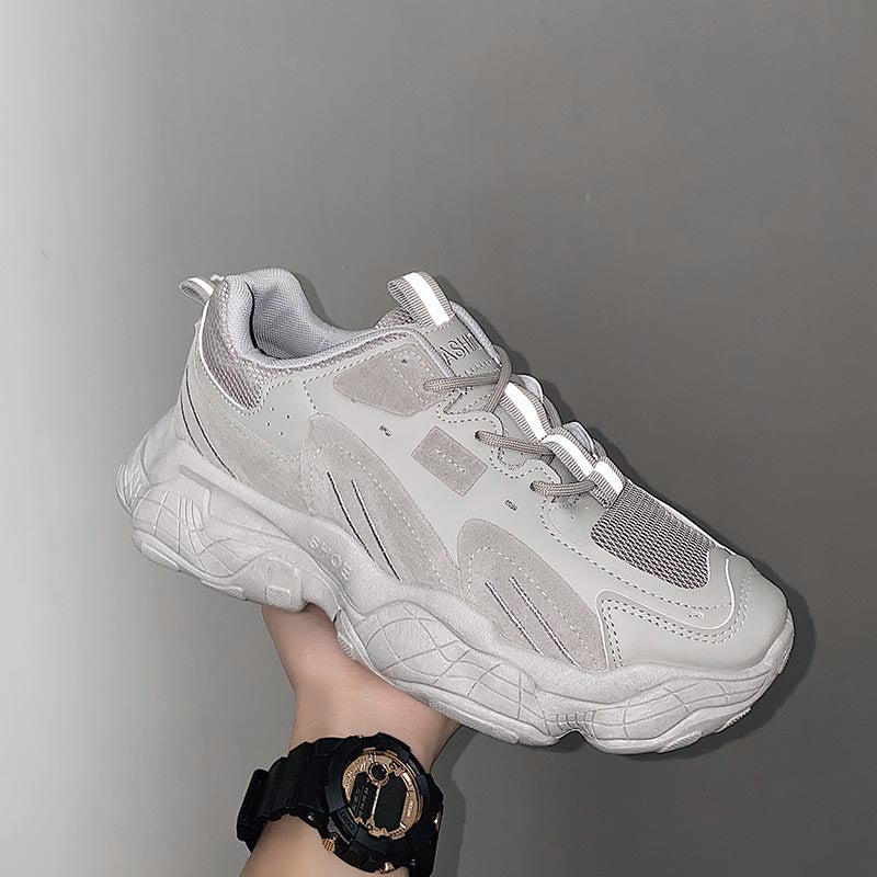 Gray sneaker held by a hand against a gray background
