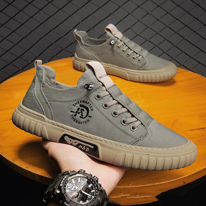 Gray sneakers on a wooden surface with a hand wearing a watch.