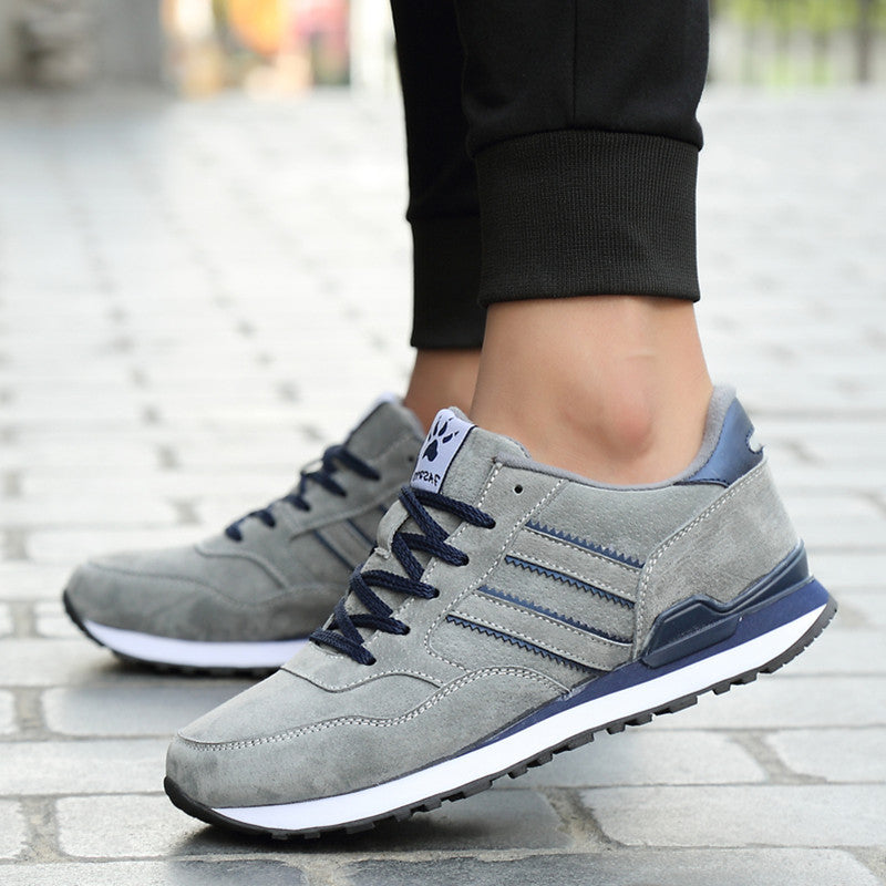 Gray sneakers with blue accents worn on a stone pavement