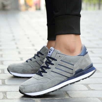 Gray sneakers with blue accents worn on a stone pavement