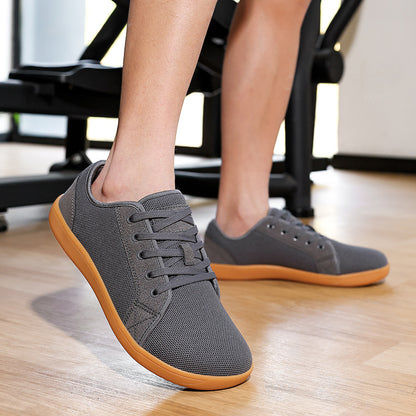 Gray sneakers with brown soles worn indoors on a wooden floor.