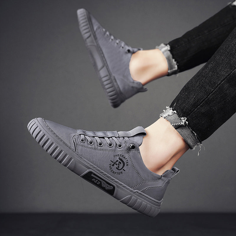 Gray sneakers worn with black jeans on a dark background