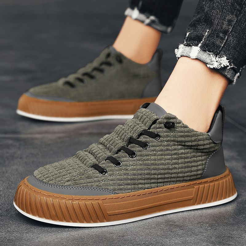 Green and brown sneakers worn by a person on a dark background