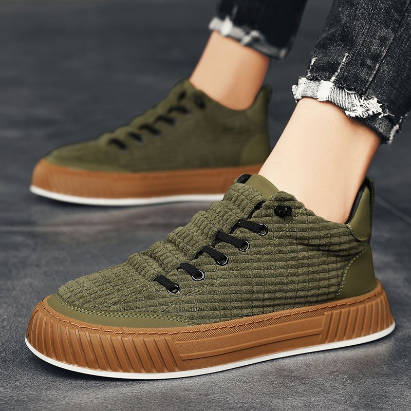 Green and brown sneakers worn by a person on a gray surface