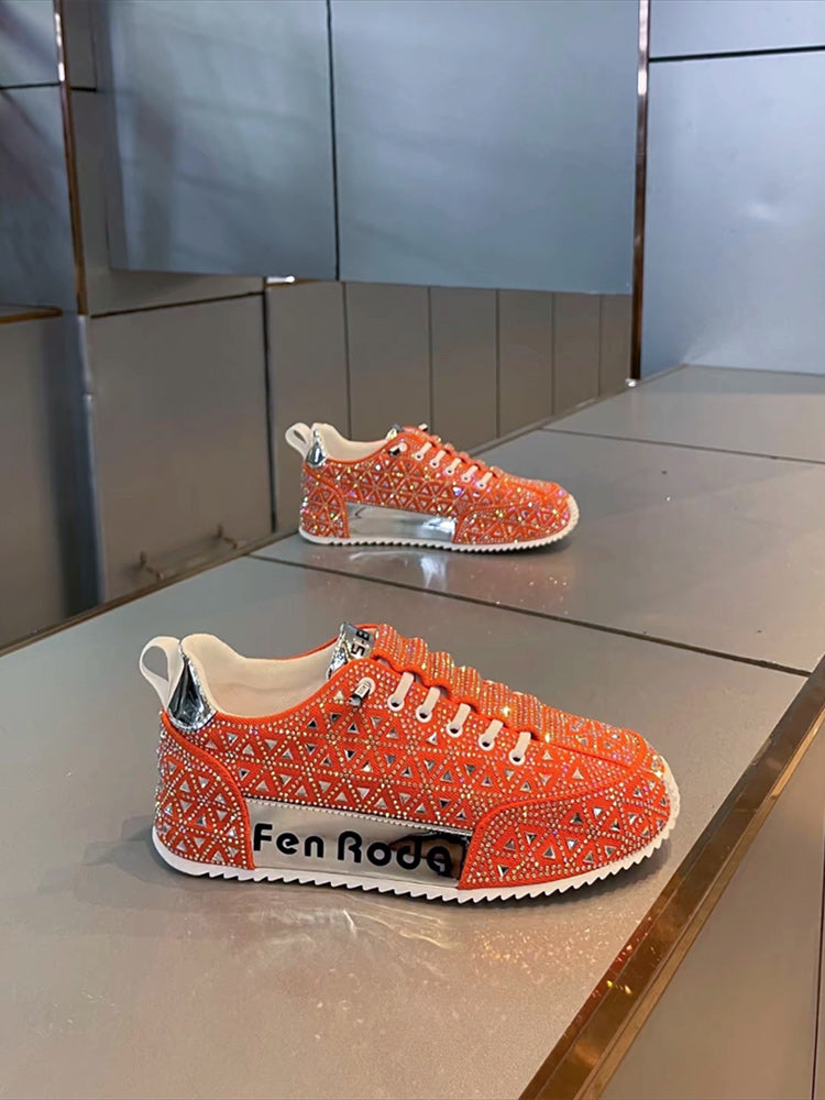 Orange sneakers with rhinestone details on a reflective surface
