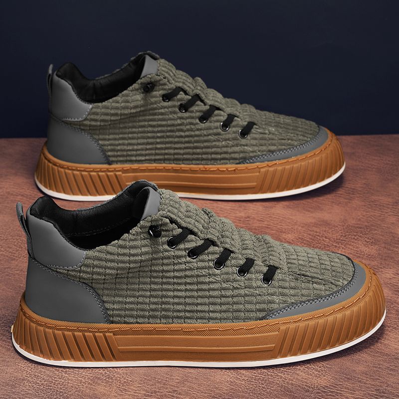 Pair of green and brown sneakers on a wooden surface with a dark background