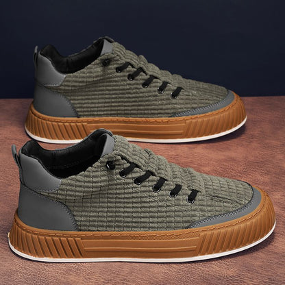 Pair of green and brown sneakers on a wooden surface with a dark background