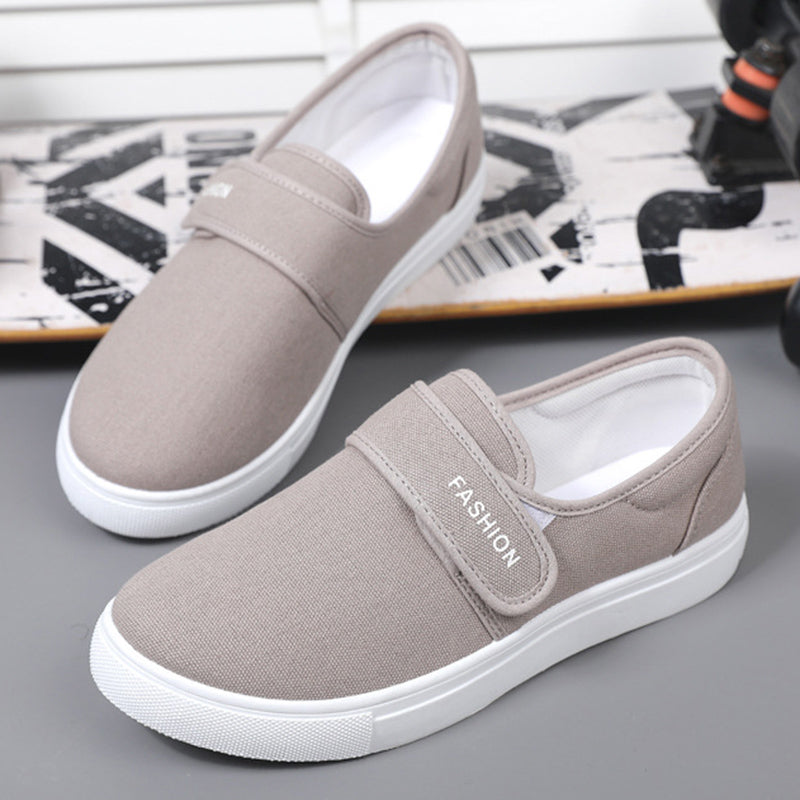 Pair of brown slip-on shoes with white soles on a gray surface.