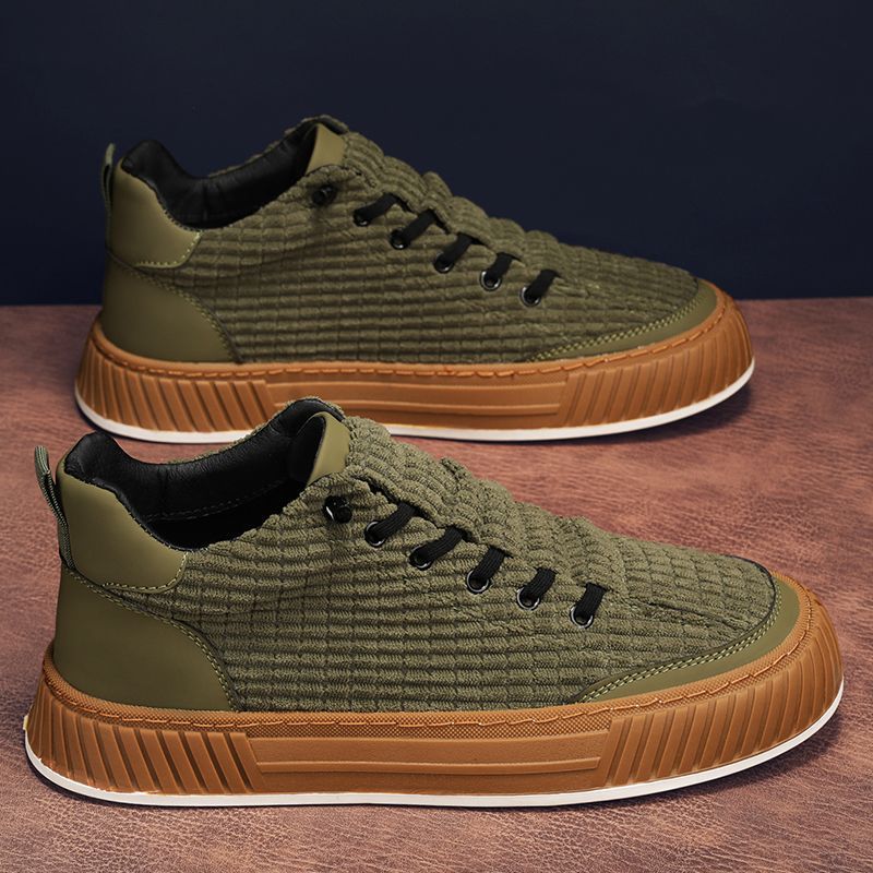 Pair of green and brown sneakers on a wooden surface with a dark background