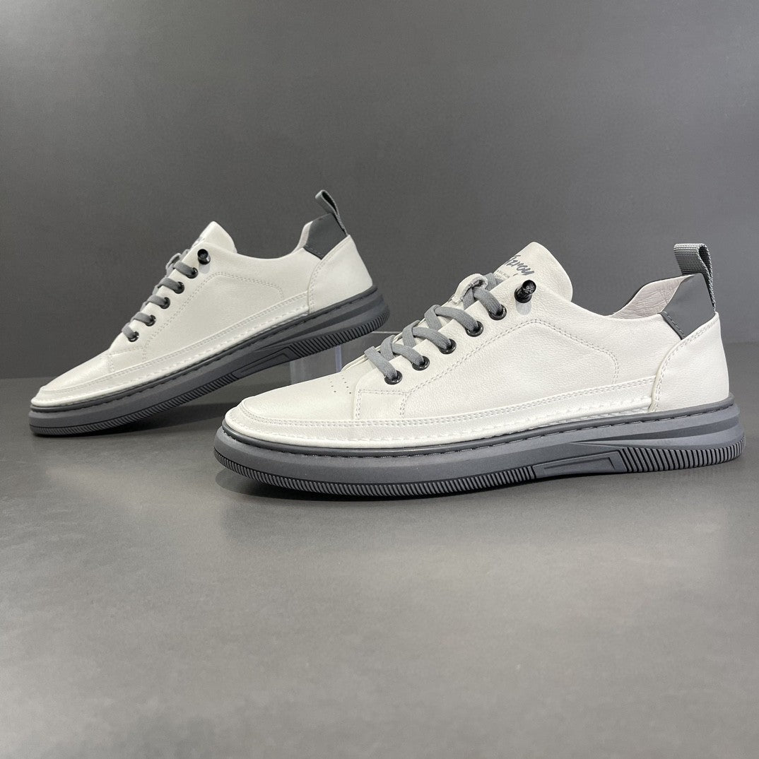 Pair of white sneakers with black soles on a gray background