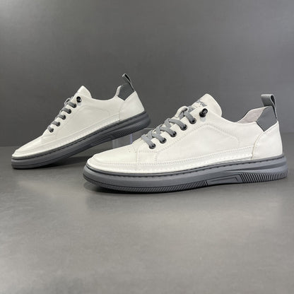 Pair of white sneakers with black soles on a gray background