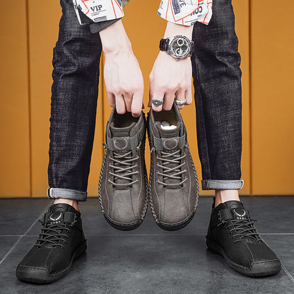 Person holding two pairs of shoes against a yellow wall.